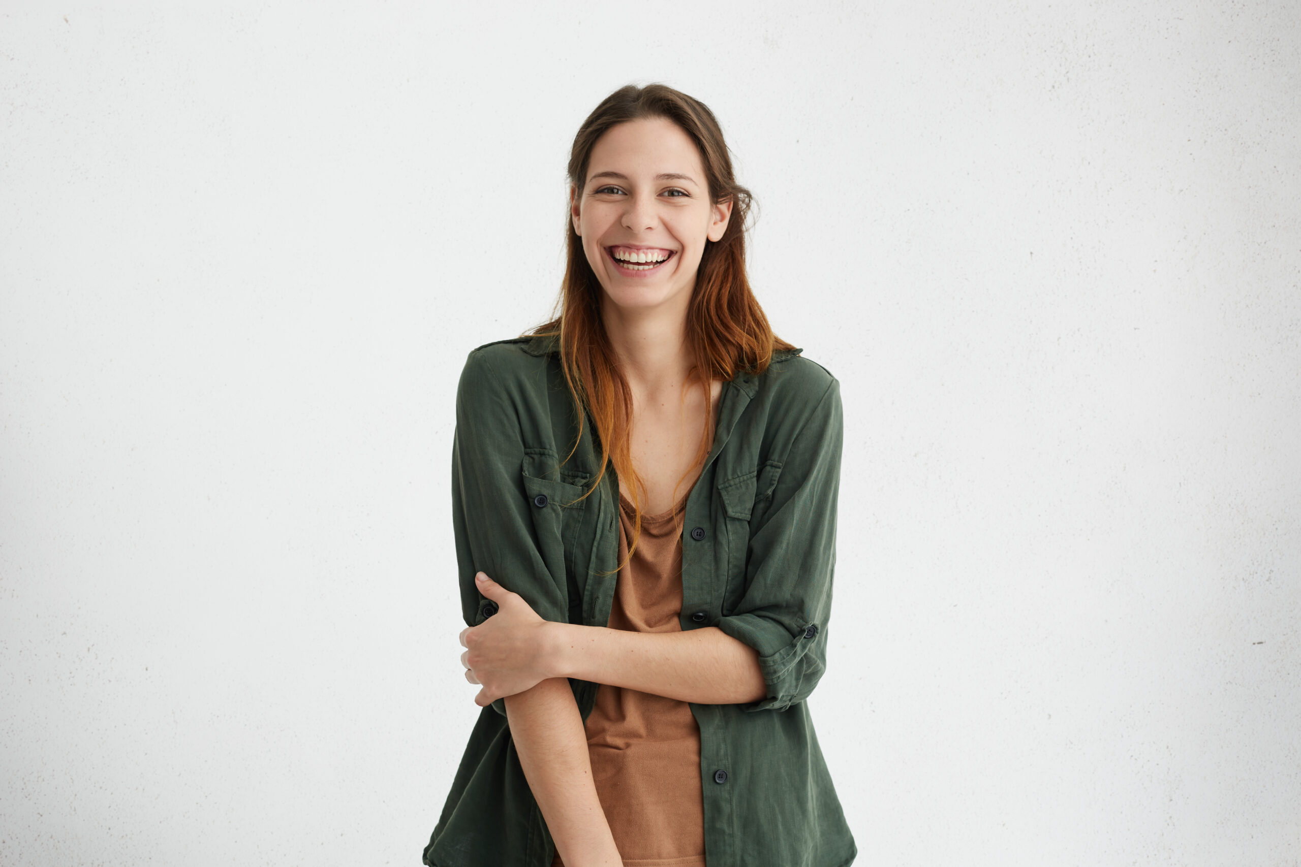 Home people, beauty and lifestyle concept. shot of attractive sensual woman with wide smile dressed in green jacket and brown t shirt smiling broadly being happy to meet her best friend. joyful nice female