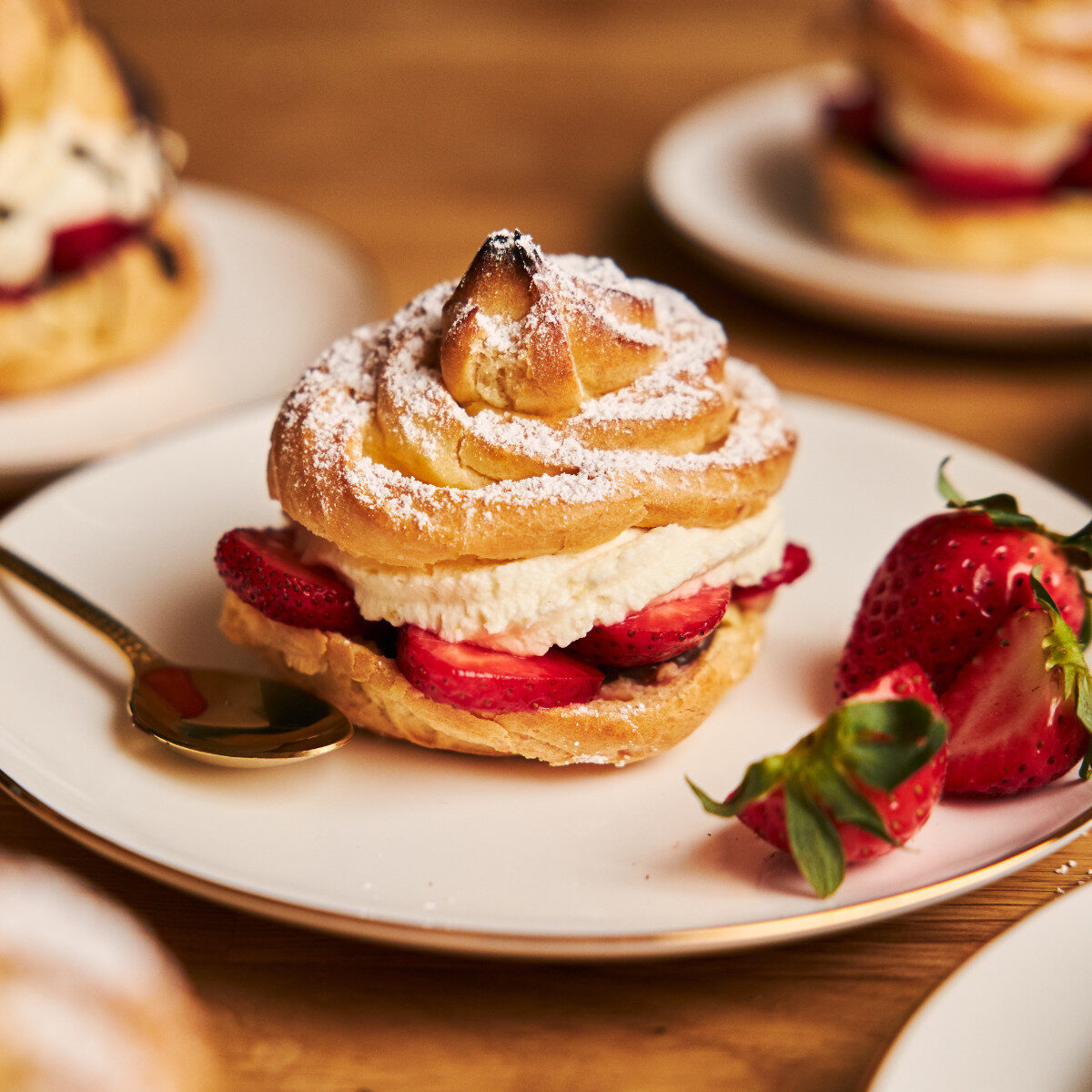 closeup shot of delicious cream puff with strawberries on a wooden table